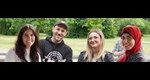 Vier junge Menschen mit verschiedenen kulturellen Hintergründen blicken in die Kamera.